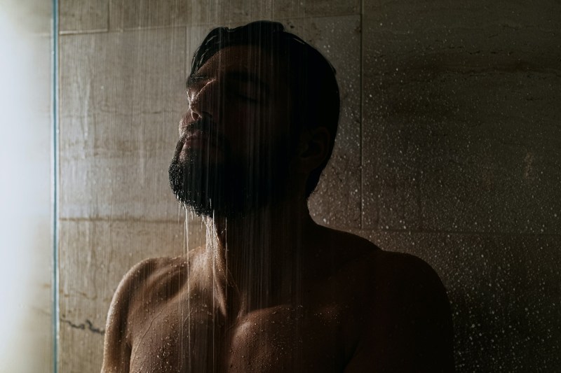 Man in shower with water over his beard